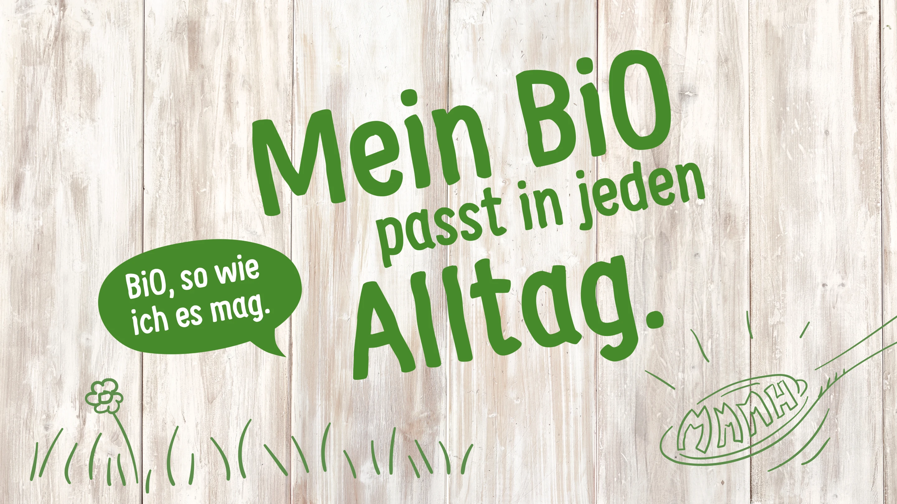 Auf einem hellen Holz-Hintergrund steht der Text "Mein BiO passt in jeden Alltag.". In einer grünen Sprechblase steht der Text "BiO, so wie ich es mag." und darunter ist eine einfache Illustration eines Kochlöffels mit den Worten "MMMH" und einer Wiese.