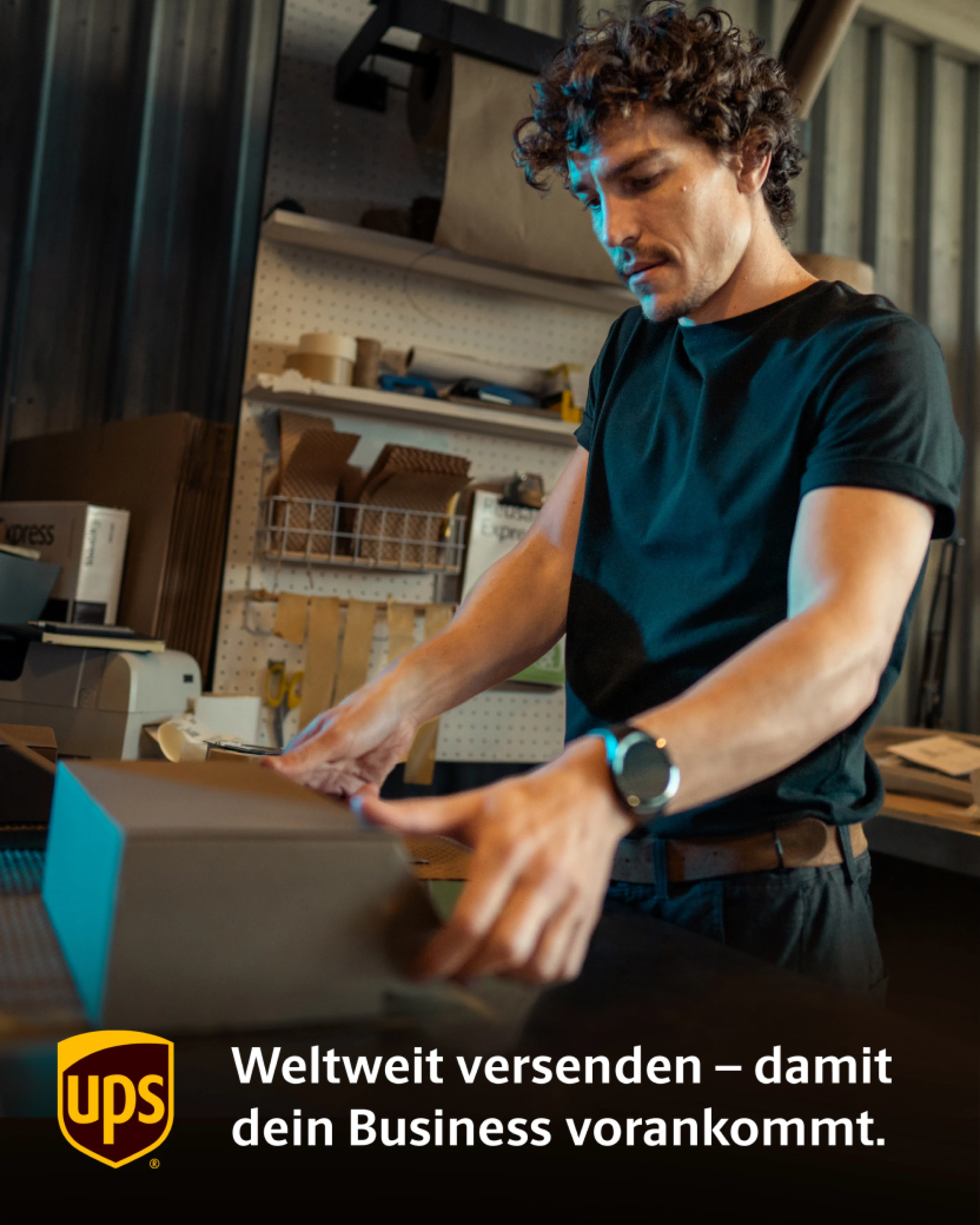 Ein Mann mit lockigen Haaren verpackt ein Paket. Der Bereich in dem er steht sieht aus, wie der Versandbereich eines kleines Unternehmens. Der Text weist darauf hin, dass UPS weltweiten Versand anbietet, um Geschäfte voranzubringen.