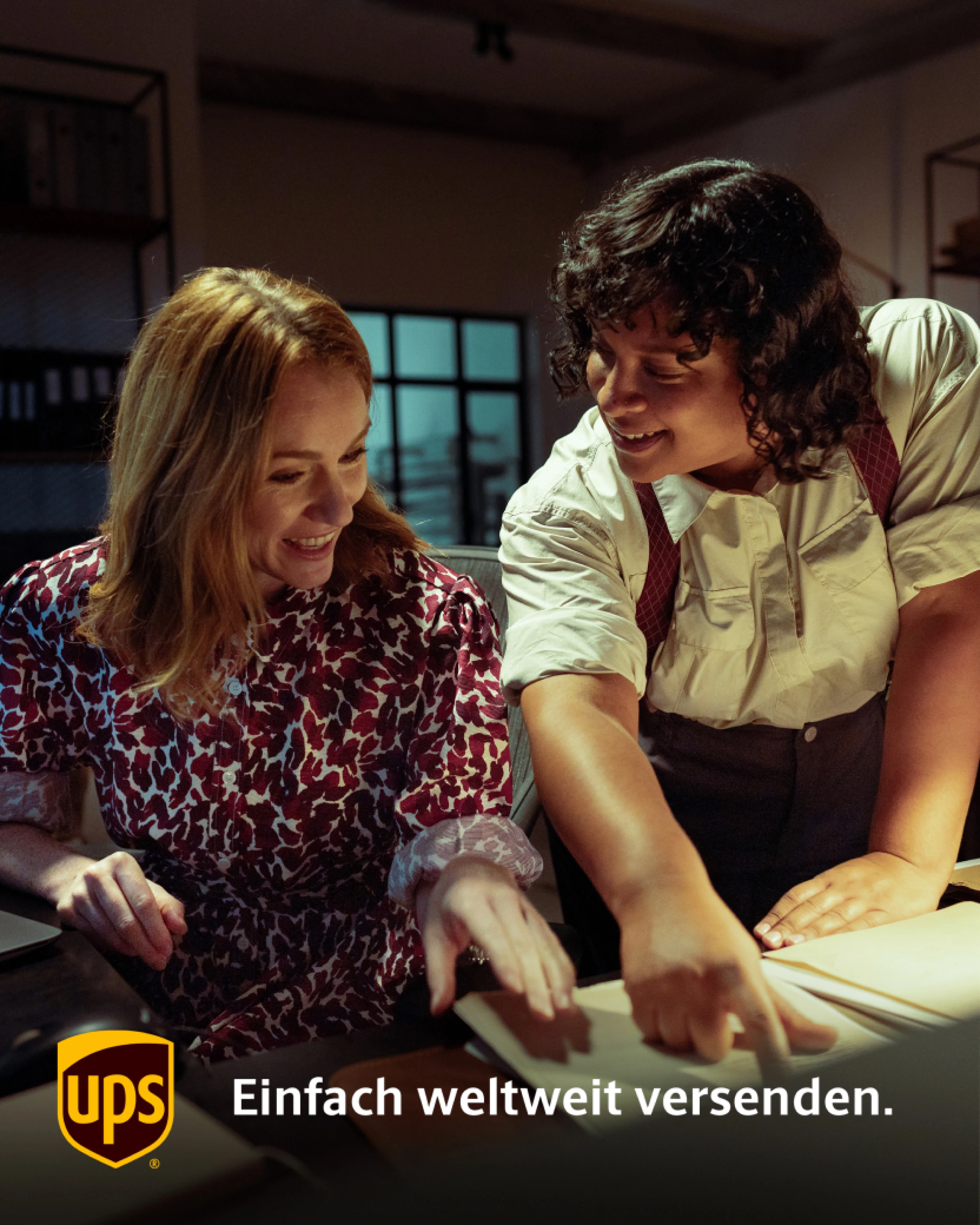 Zwei lächelnde Frauen arbeiten gemeinsam an einem Tisch, während sie auf Dokumente zeigen. Im Hintergrund sind Regale und Fenster sichtbar. Das UPS-Logo und der Slogan "Einfach weltweit versenden" sind eingeblendet.